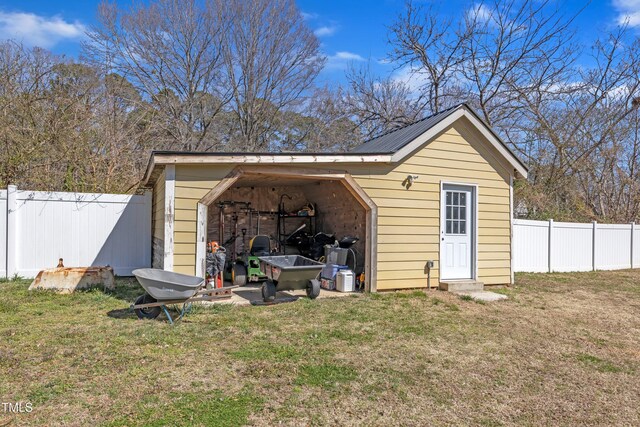 view of outdoor structure with fence private yard and an outbuilding