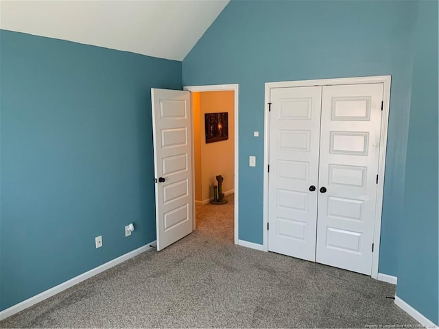 unfurnished bedroom with vaulted ceiling, a closet, carpet, and baseboards