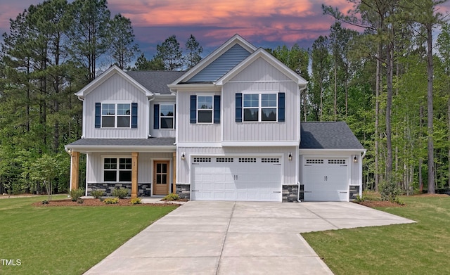 craftsman-style home featuring driveway, stone siding, board and batten siding, and a front yard