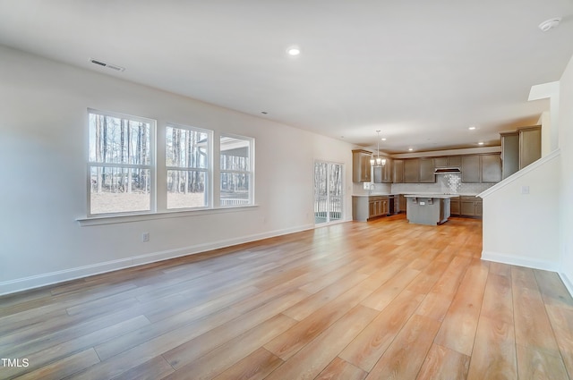 unfurnished living room featuring light wood-type flooring, baseboards, and visible vents