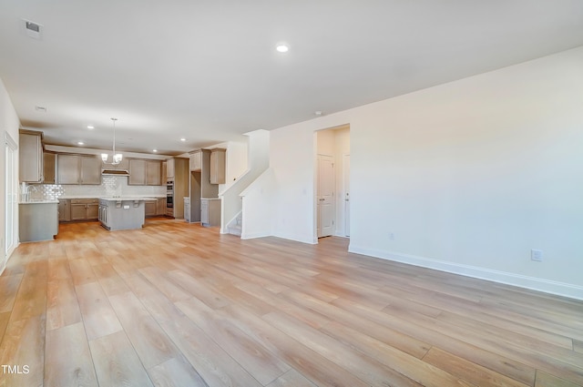 unfurnished living room featuring recessed lighting, stairway, light wood-type flooring, and baseboards