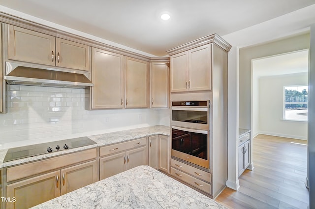 kitchen featuring black electric stovetop, backsplash, light wood-style floors, stainless steel double oven, and under cabinet range hood