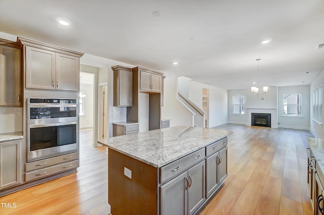 kitchen with tasteful backsplash, stainless steel double oven, and light wood-style flooring