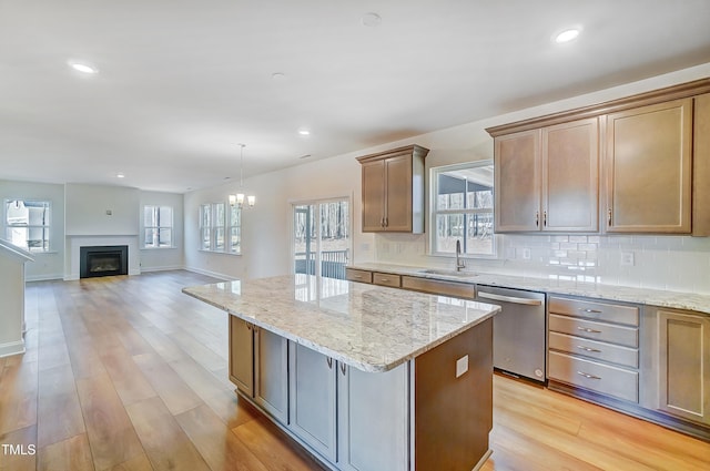 kitchen featuring light wood-style flooring, decorative backsplash, dishwasher, and a center island