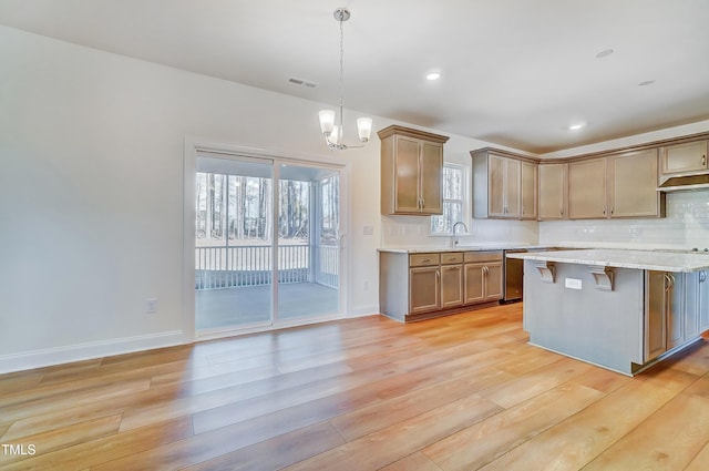 kitchen featuring visible vents, hanging light fixtures, decorative backsplash, stainless steel dishwasher, and light wood-style floors