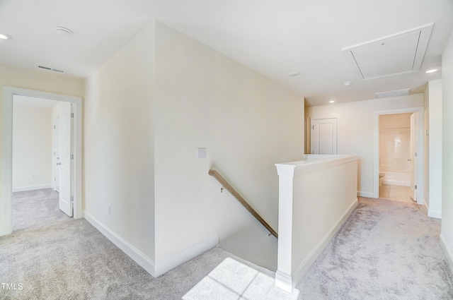 hallway with attic access, baseboards, visible vents, carpet flooring, and an upstairs landing