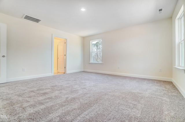 carpeted empty room with baseboards, visible vents, and recessed lighting