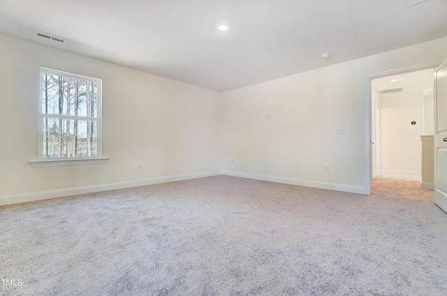 empty room featuring light colored carpet, visible vents, baseboards, and recessed lighting