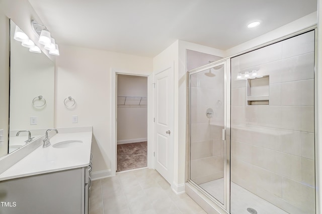 bathroom featuring a walk in closet, baseboards, a shower stall, and vanity