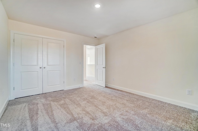 unfurnished bedroom with recessed lighting, a closet, carpet flooring, and baseboards