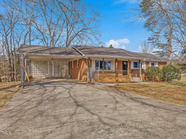 ranch-style house with aphalt driveway, brick siding, covered porch, a front yard, and a carport