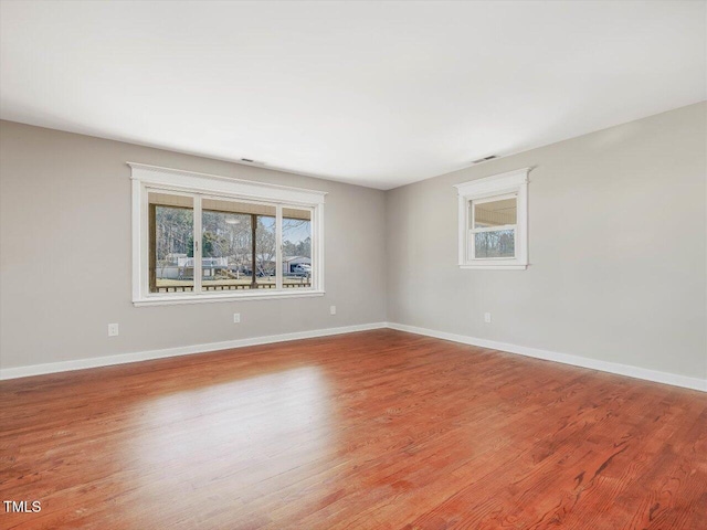 empty room featuring light wood-style floors, visible vents, and baseboards