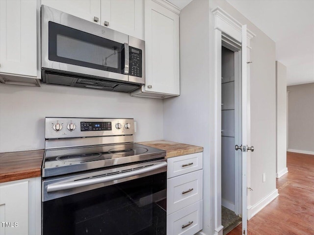 kitchen featuring appliances with stainless steel finishes, butcher block countertops, and white cabinetry