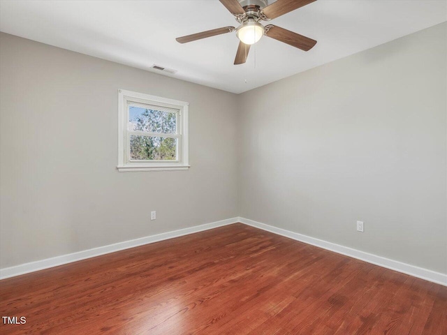 empty room featuring a ceiling fan, visible vents, baseboards, and wood finished floors