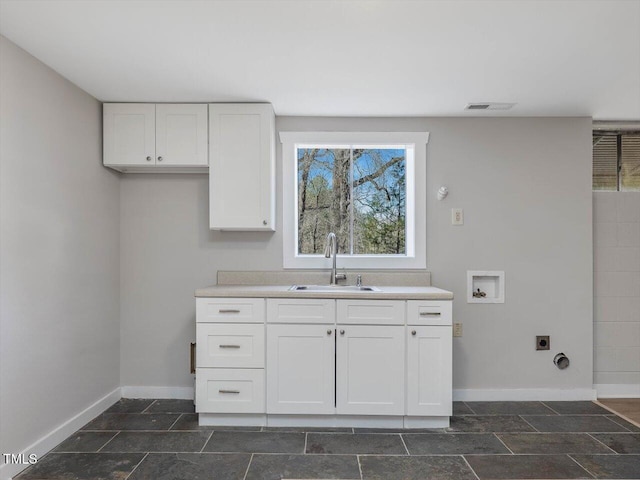 kitchen with visible vents, a sink, white cabinetry, and baseboards