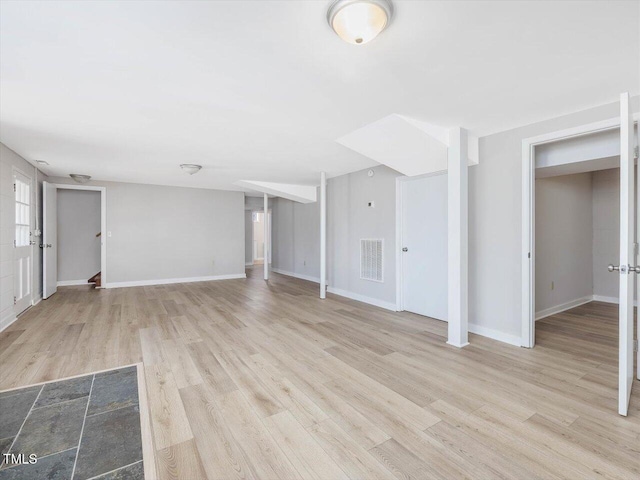 unfurnished living room featuring wood finished floors, visible vents, and baseboards