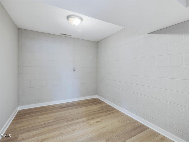 empty room featuring light wood-style floors, visible vents, and baseboards