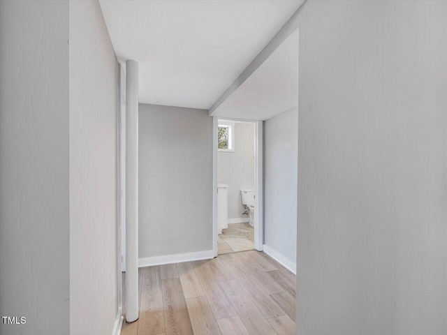 corridor featuring light wood finished floors and baseboards