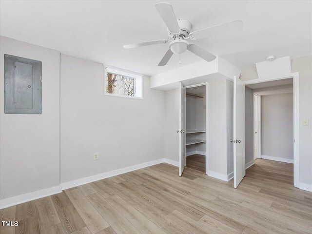 unfurnished bedroom with light wood finished floors, electric panel, baseboards, and a ceiling fan