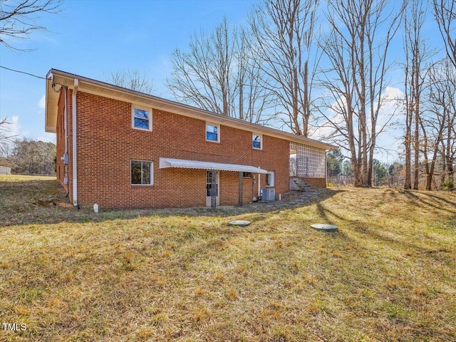 back of property with a yard, brick siding, and central AC unit