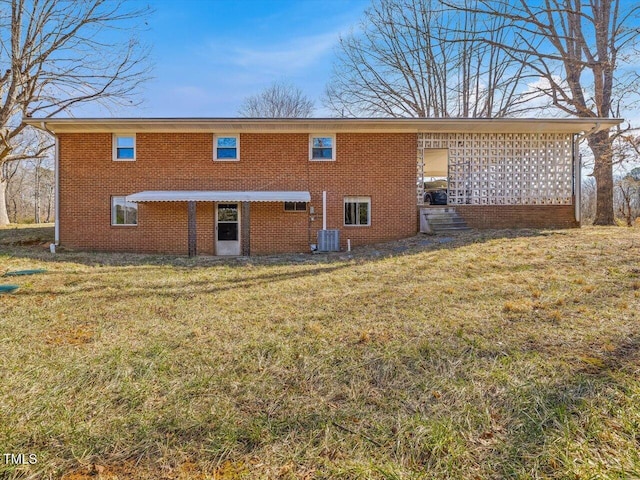 rear view of property with cooling unit, a lawn, and brick siding