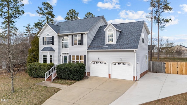 view of front of house featuring a shingled roof, concrete driveway, fence, and an attached garage