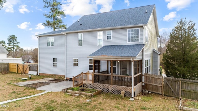 back of house with a vegetable garden, a sunroom, a fenced backyard, roof with shingles, and a patio area