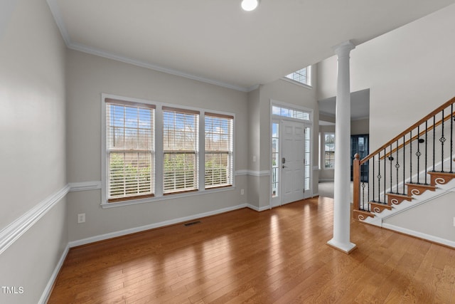 entrance foyer featuring hardwood / wood-style flooring, visible vents, baseboards, stairs, and decorative columns