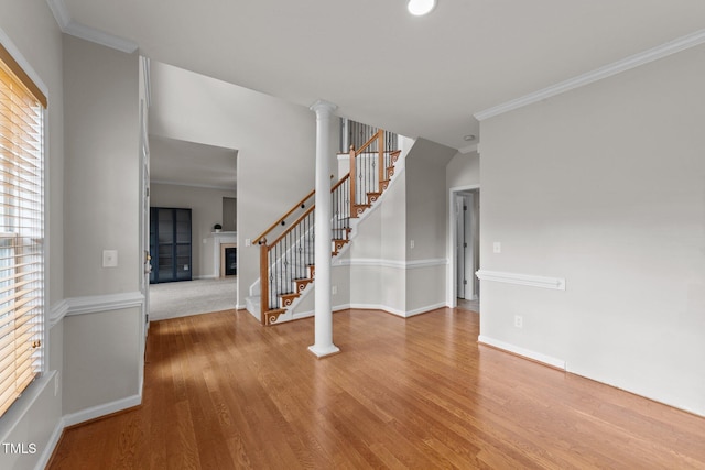 interior space with wood finished floors, a fireplace, crown molding, and stairs