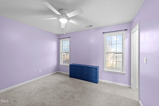 carpeted spare room featuring ceiling fan, visible vents, and baseboards