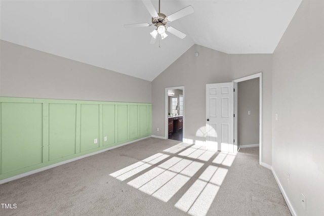 unfurnished bedroom featuring high vaulted ceiling, carpet, ensuite bath, and a ceiling fan