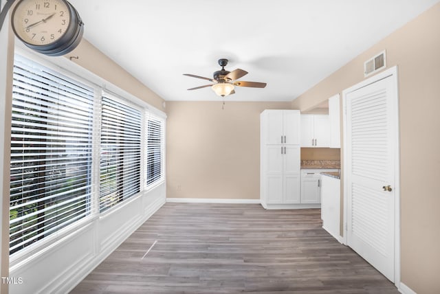 interior space with light wood-style flooring, a ceiling fan, visible vents, and baseboards