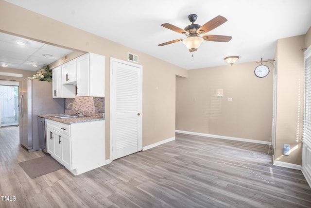 kitchen with visible vents, stainless steel dishwasher, white cabinets, a sink, and baseboards