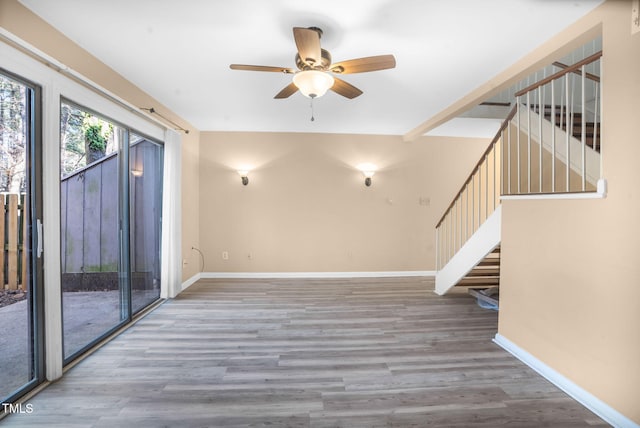 spare room featuring stairs, wood finished floors, and baseboards