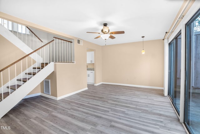 spare room featuring a ceiling fan, visible vents, baseboards, and wood finished floors