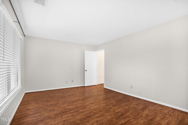 empty room featuring visible vents, baseboards, and wood finished floors