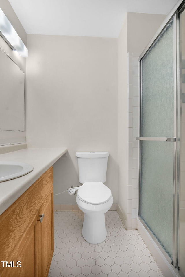 full bath featuring toilet, vanity, baseboards, tile patterned floors, and a stall shower