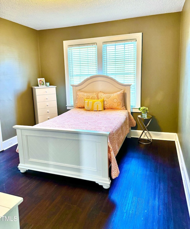 bedroom with a textured ceiling, dark wood-style flooring, and baseboards