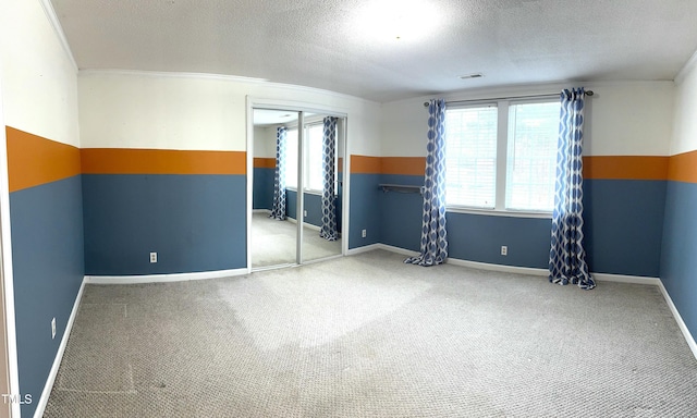 unfurnished bedroom with a textured ceiling, a closet, carpet flooring, and baseboards