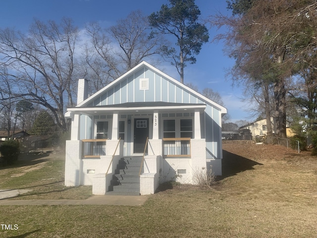 view of front of house featuring brick siding, a porch, board and batten siding, crawl space, and a front lawn