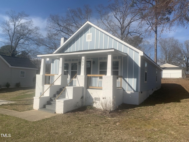 bungalow-style house with a chimney, crawl space, a porch, board and batten siding, and brick siding