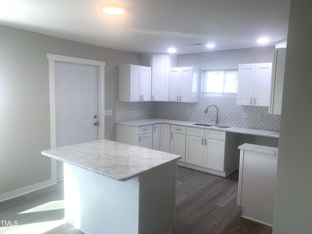 kitchen featuring decorative backsplash, dark wood-type flooring, white cabinetry, a sink, and light stone countertops