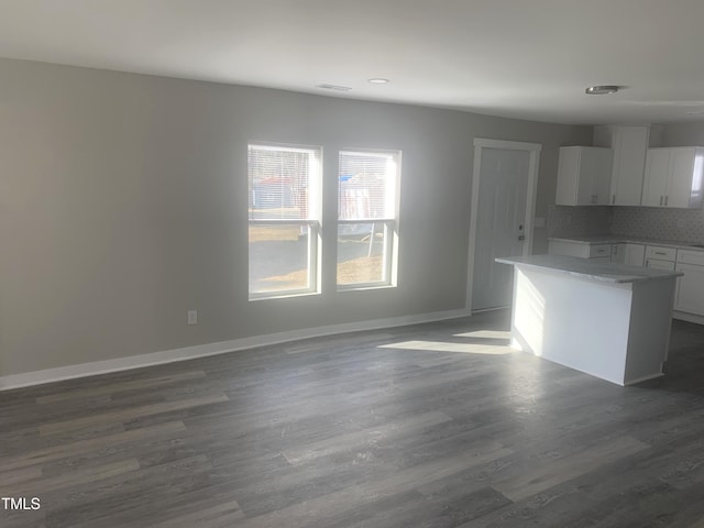 kitchen featuring dark wood finished floors, light countertops, backsplash, white cabinetry, and baseboards