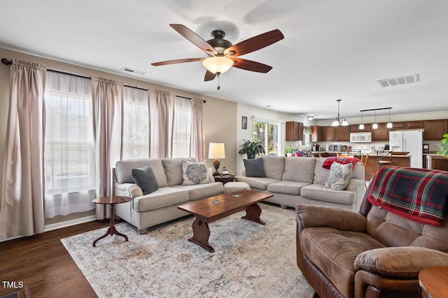 living room with dark wood-style floors, ceiling fan, and visible vents