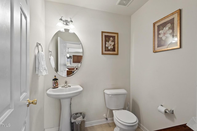 bathroom with toilet, baseboards, visible vents, and a sink