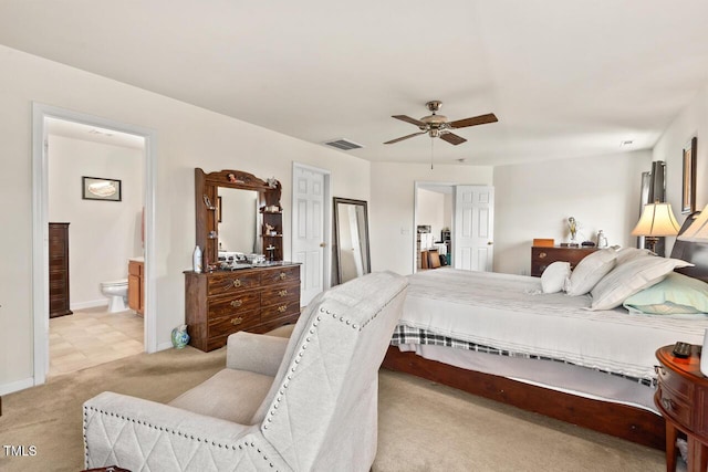 carpeted bedroom with a ceiling fan, visible vents, baseboards, and ensuite bathroom