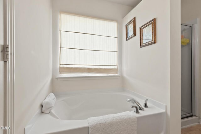 bathroom with a shower stall and a bath