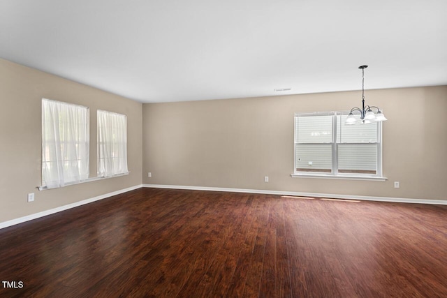 634 Conover Rd, Durham, NC 27703 - empty room featuring healthy amount of natural light, a chandelier, dark wood-style flooring, and baseboards