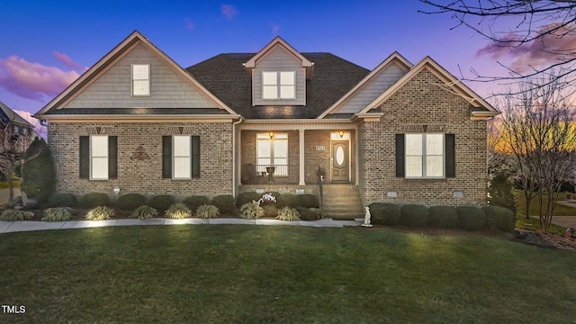 view of front of property featuring covered porch, a front lawn, and brick siding