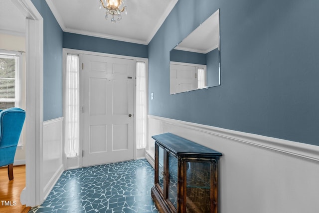 foyer with ornamental molding, wainscoting, and an inviting chandelier